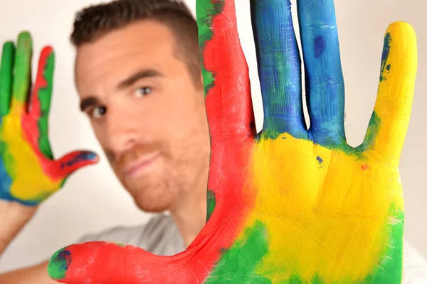 Man looking into the camera with painted hands — Stock Photo, Image