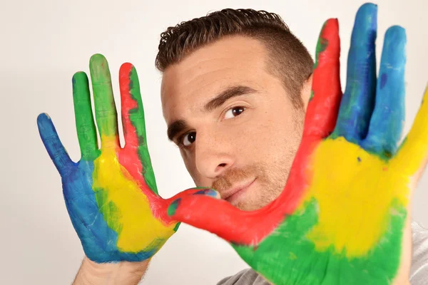 Man looking into the camera with painted hands — Stock Photo, Image