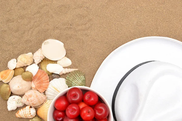 Red plums, old camera, shells and white hat on sand — Stock Photo, Image