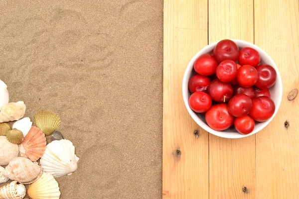 Prunes et coquilles sur bois et sable — Photo