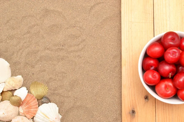 Plums and shells on wood and sand — Stock Photo, Image