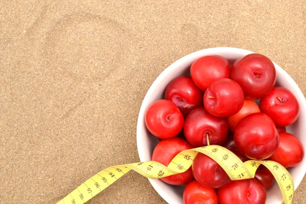 Red plums and tape measure — Stock Photo, Image