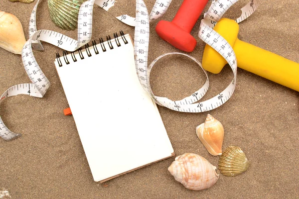 Notebook a činky na písku — Stock fotografie