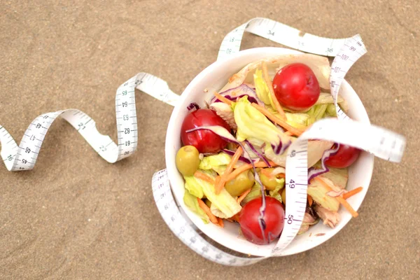 Salad and tape measure on sand — Stock Photo, Image