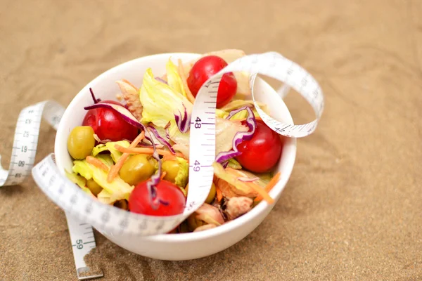 Salad and tape measure on sand — Stock Photo, Image