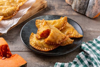 Ahşap masada balkabağı empanadillası.