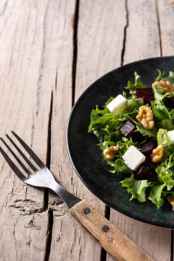 Beyaz peynirli pancar salatası, marul ve ceviz kırsal ahşap masada.
