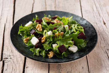 Beyaz peynirli pancar salatası, marul ve ceviz kırsal ahşap masada.