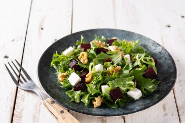 Beyaz peynirli pancar salatası, marul ve ceviz kırsal ahşap masada.