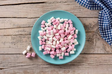 Ahşap masada mavi bir tabakta tatlı marşmelovlar