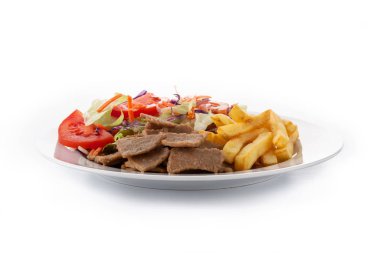 Beyaz arka planda bir tabak kebap, sebze ve patates kızartması.