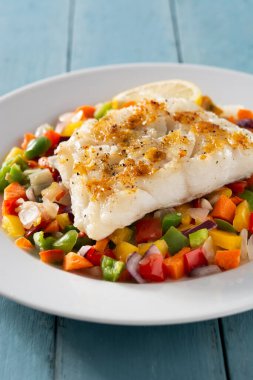 Mavi ahşap masada sebzeli ızgara morina.