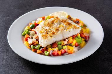 Siyah taşlı tabakta sebzeli ızgara morina balığı.