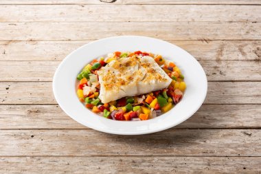 Ahşap masada sebzeli ızgara morina.