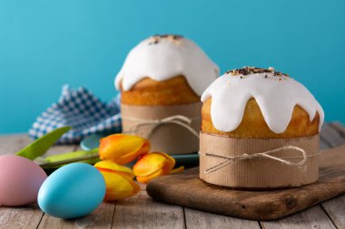 Geleneksel Paskalya pastası, ahşap masada renkli yumurtalar ve laleler..