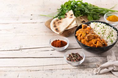 Tahta masadaki siyah kasede Hint tereyağlı tavuk. Boşluğu kopyala