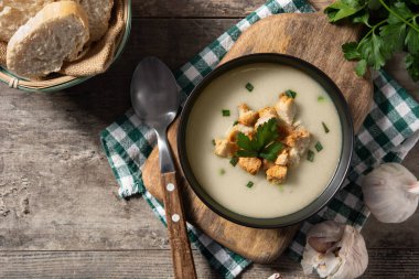 Tahta masadaki siyah kasede kıtır ekmekli sarımsak çorbası. Üst Manzara. Boşluğu kopyala