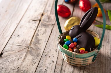 Paskalya çikolatalı tavşan ve ahşap masada renkli yumurtalar. Boşluğu kopyala