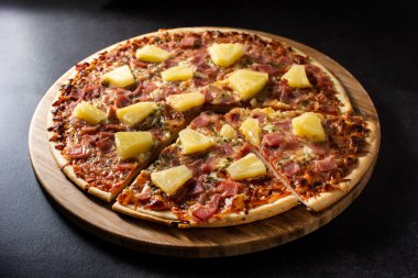 Siyah arka planda ananas, jambon ve peynirli Hawaii pizzası.