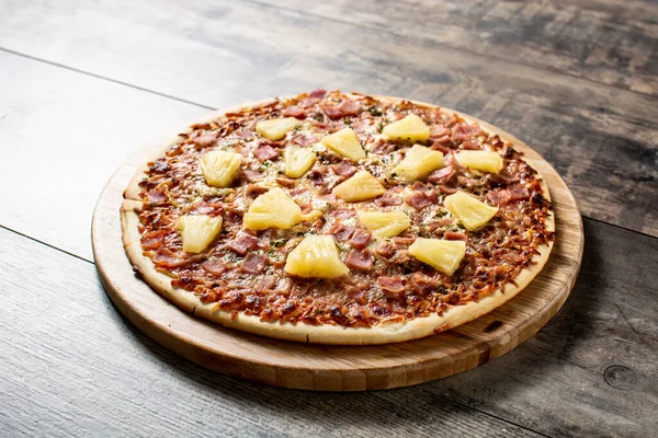 Hawaiian pizza with pineapple,ham and cheese on wooden table