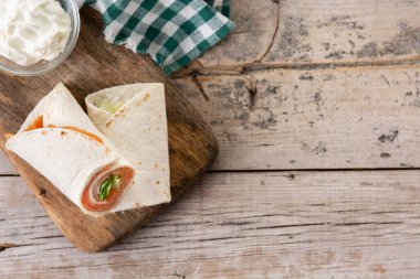 Somonlu sandviç rulosu, peynirli ve sebzeli, ahşap masa manzaralı. Boşluğu kopyala