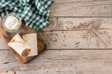 Somonlu sandviç rulosu, peynirli ve sebzeli, ahşap masa manzaralı. Boşluğu kopyala