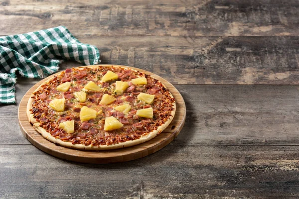 Hawaiian pizza with pineapple,ham and cheese on wooden table.Copy space