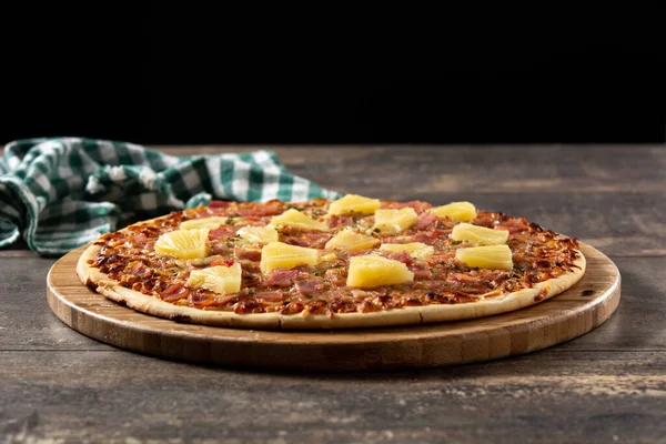 Hawaiian pizza with pineapple,ham and cheese on wooden table