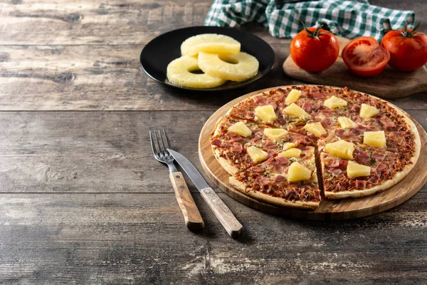 Hawaiian pizza with pineapple,ham and cheese on wooden table. Copy space