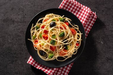 Siyah zemin üzerinde sebzeli spagetti (brokoli, domates, biber)