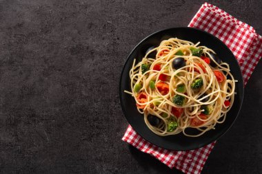 Siyah arka planda sebzeli spagetti (brokoli, domates, biber). Üst manzara. Boşluğu kopyala
