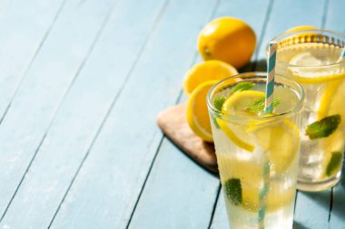 Mavi ahşap masada bir bardak taze limonata. Boşluğu kopyala