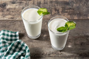 Ayran, nane şekeri ve ahşap masadaki salatalıkla içer.