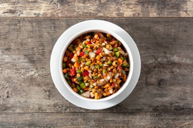 Biberli mercimek salatası, soğan ve havuç, ahşap bir masada.