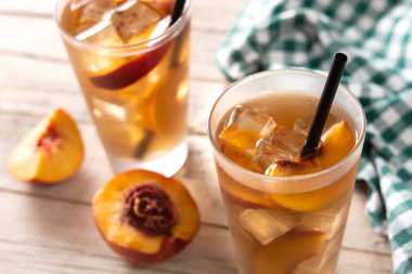 Bir bardak şeftali çayı ve ahşap masada buz küpleri.