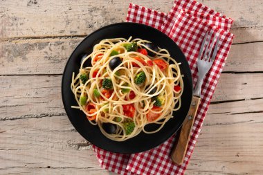 Sebzeli spagetti (brokoli, domates, biber) ahşap masada.