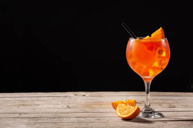 Ahşap masa ve siyah arka planda bir bardak aperol spreyi kokteyli. Boşluğu kopyala