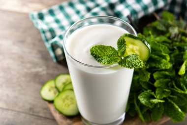 Ayran, nane şekeri ve ahşap masadaki salatalıkla içer.