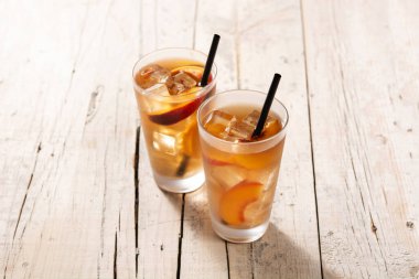 Bir bardak şeftali çayı ve ahşap masada buz küpleri.