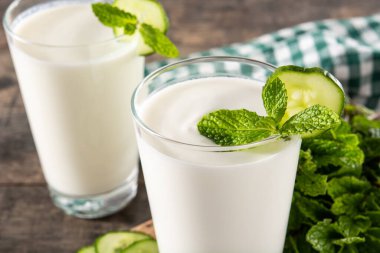 Ayran, nane şekeri ve ahşap masadaki salatalıkla içer.