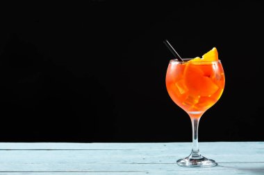 Mavi ahşap masa ve siyah arka planda bir bardak aperol spreyi kokteyli. Boşluğu kopyala