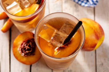 Bir bardak şeftali çayı ve ahşap masada buz küpleri.