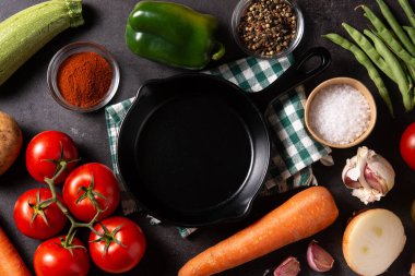 Siyah taş arka planda çeşitli sebze, bitki ve baharatlar.