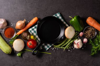 Sebze, bitki ve baharat çeşitleri. Siyah arka planda demir tava var. Üst Manzara. Boşluğu kopyala