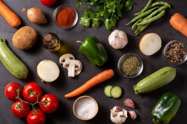 Siyah arka planda çeşitli sebze, bitki ve baharatlar var.