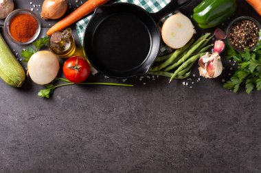 Sebze, bitki ve baharat çeşitleri. Siyah arka planda demir tava var. Üst Manzara. Boşluğu kopyala