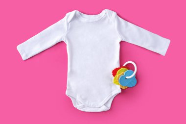 Beyaz bebek kıyafetleri ve pembe arka planda renkli anahtarlar.