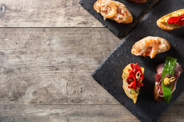 Ahşap masada İspanyol pintxos çeşitleri. Üst Manzara. Boşluğu kopyala