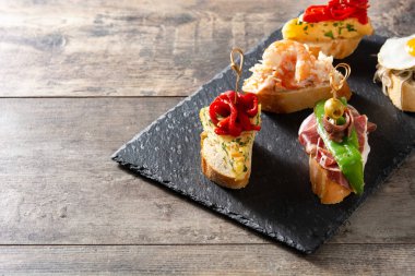 Ahşap masada İspanyol pintxos çeşitleri. Boşluğu kopyala