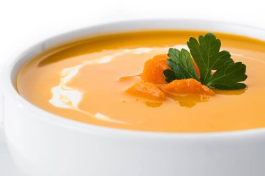 Carrot soup with cream and parsley isolated on white background. Copy space